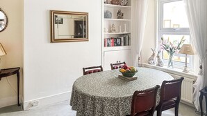 Un comedor con una mesa redonda, sillas, un espejo y una estantería.