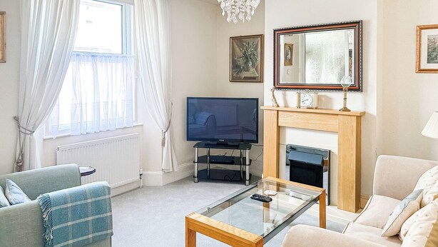 Una sala de estar con televisión, sofá y chimenea.