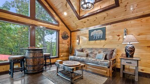 L’intérieur d’un chalet confortable en rondins de bois, avec une grande fenêtre, des meubles en bois et une décoration murale sur le thème des ours.