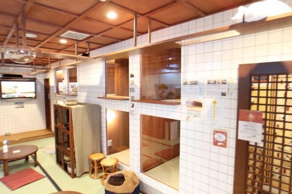 A traditional Japanese room with tatami flooring, a low wooden table, a cushioned seating area, and a sliding door with a grid pattern. - Cat Spa & Cat Ryokan Neco Republic Osaka (Osaka)