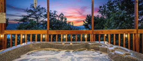 A hot tub with a view of a sunset and trees.