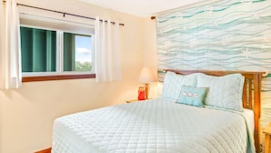 Een slaapkamer met een groot bed, een raam met gordijnen, een nachtkastje met een lamp en een muur met een golvend patroon.