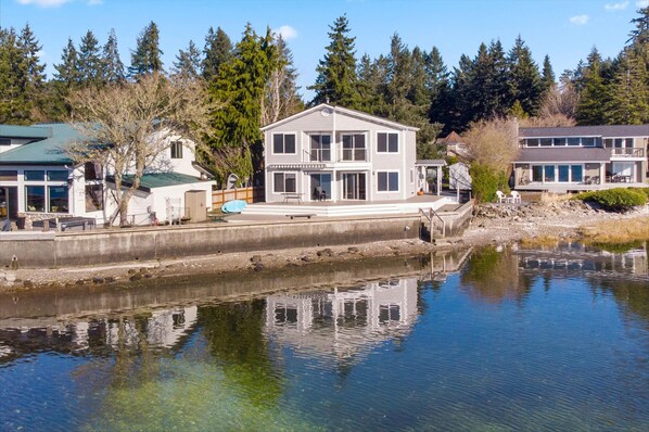 A two-story house with a balcony, a dock, and a clear view of the water. - Belfair Beach House in Belfair (Belfair)