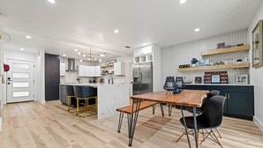 A modern kitchen with a dining area, featuring a wooden table, black chairs, and a built-in island with a sink. - Tipperary Oasis: 3 Beds & a Private Pool (Dallas)