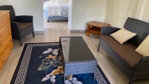 A room with a bed, a sofa, a small table, a dresser, and a patterned rug. - Pristine 1 Bed Cottage in Northern Suburbs - 2222 (Harare)