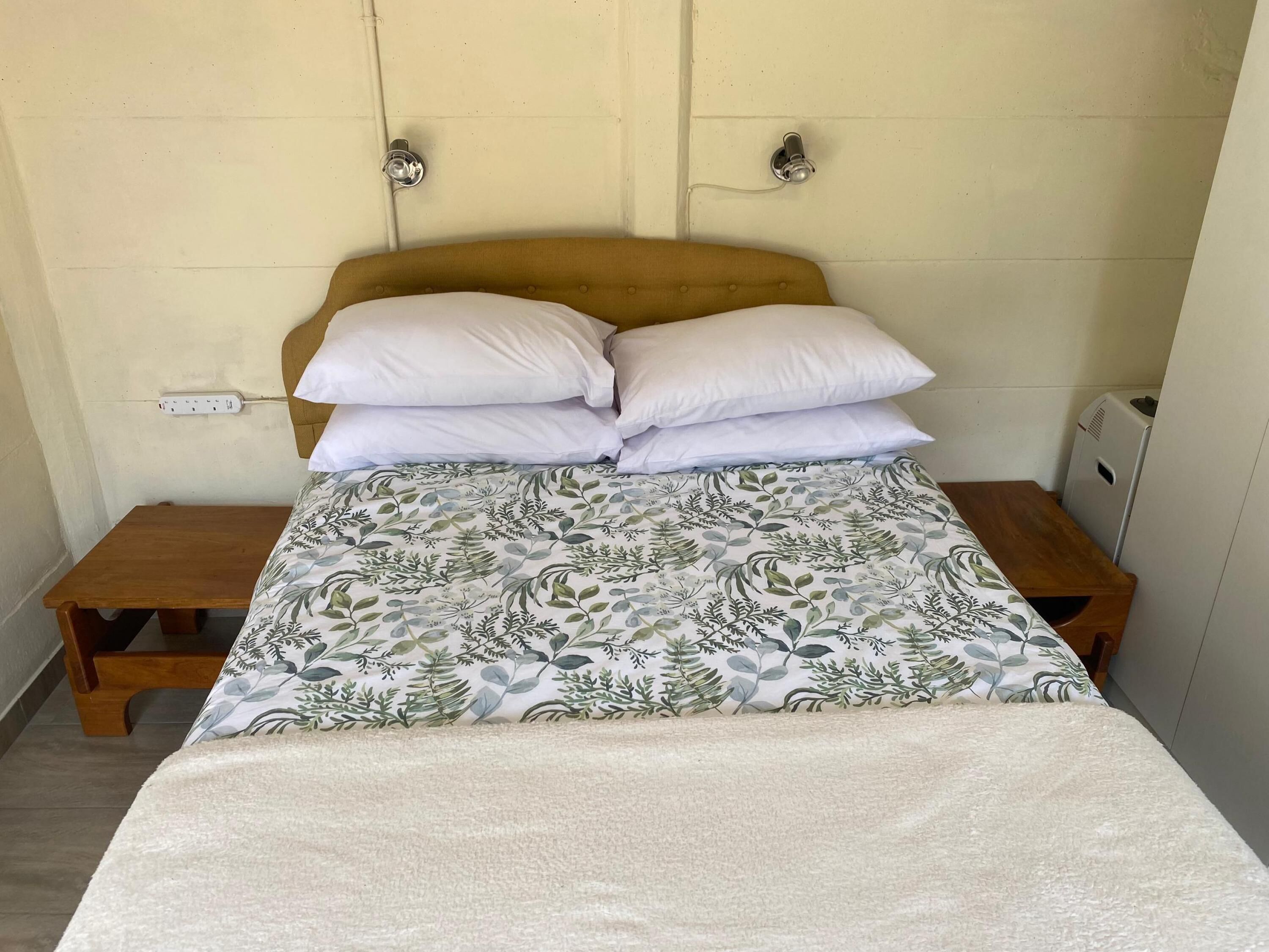 A bed with a floral bedspread, two white pillows, and a wooden headboard.