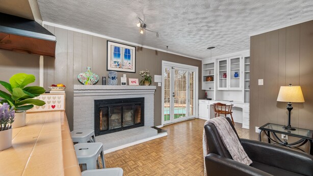 A living room with a fireplace, a dining area with a table and chairs, and a kitchen area with cabinets and a countertop. - White Rock Poolside Retreat- 4 Beds & a Private Pool (Dallas)