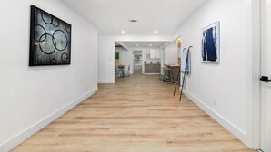 A spacious hallway with wooden flooring, white walls, and artwork. - Forest Hill Family Hideaway- 4-Bed Retreat (Dallas)