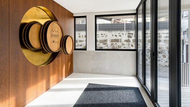 A modern interior with wooden accents, a stone wall, and large windows offering a view of the outside. - GuestReady - comfort near Jardim do Morro (Vila Nova de Gaia)