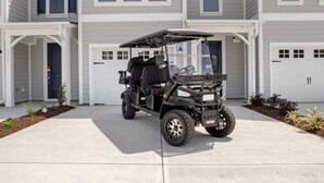 A golf cart parked in a driveway in front of a two-story building with garage doors. - Tee & Sea Paradise- Pool- Slps 11- Golf View-Grill (North Myrtle Beach)
