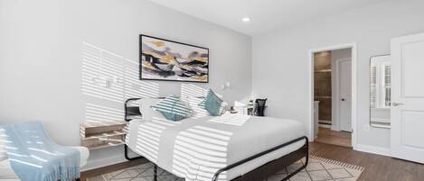 A modern bedroom with a bed, a desk, and a ceiling fan.