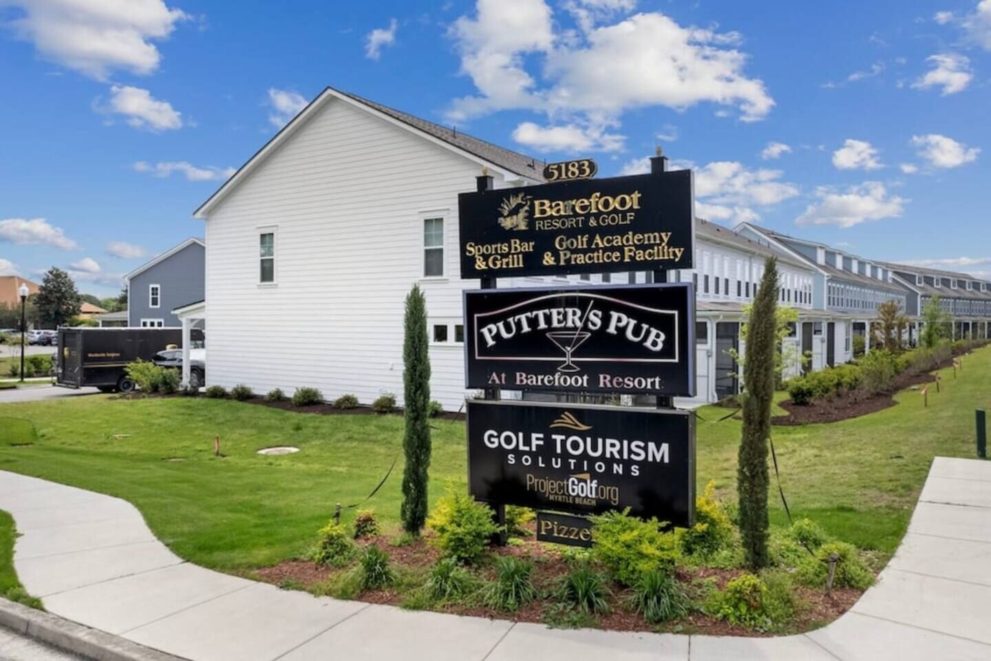 A building with a sign for Barefoot Resort & Golf, a sports bar, golf academy, and practice facility.