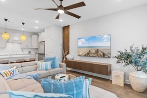 Una sala moderna con un sofá, una mesa de centro y un cuadro de una escena de playa.