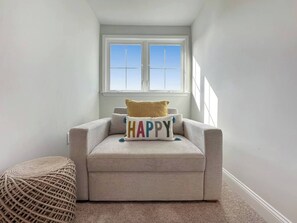 A corner room with a window, a sofa, a cushion with 'HAPPY' text, and a woven pouf. - Tee & Sea Paradise- Pool- Slps 11- Golf View-Grill (North Myrtle Beach)