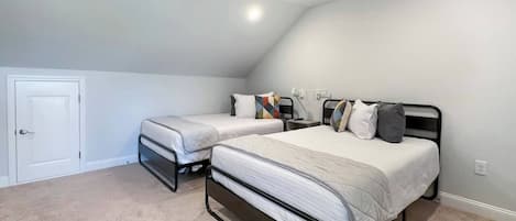 Un dormitorio con dos camas individuales, ventilador de techo e iluminación empotrada.
