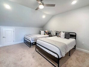A bedroom with two single beds, a ceiling fan, and recessed lighting.
