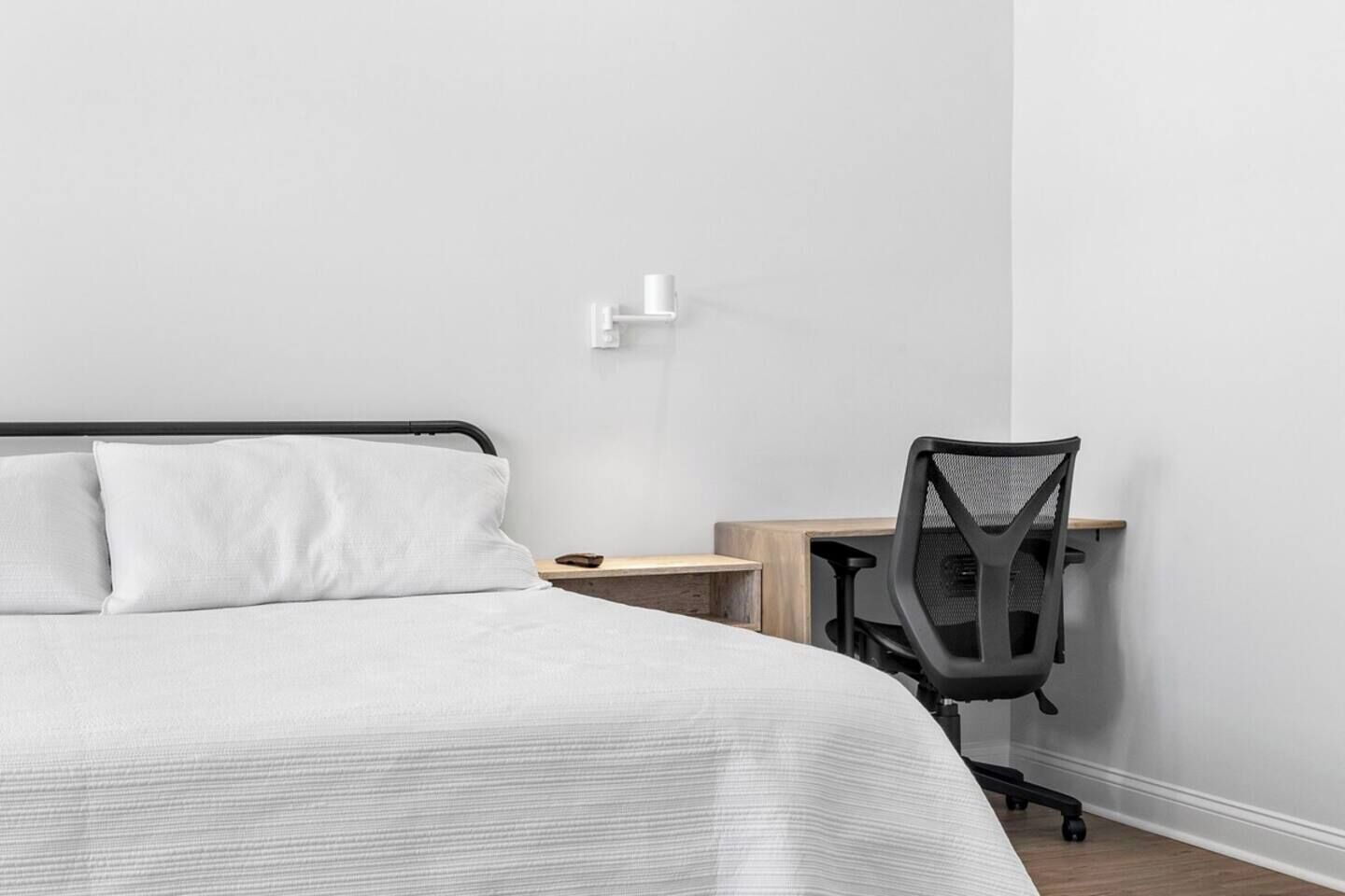 A bedroom with a bed, a desk, and a chair.