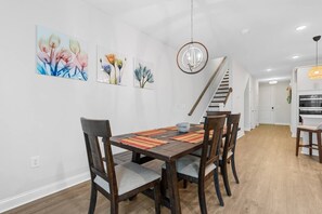 A dining area with a wooden table, chairs, and a hanging light fixture.