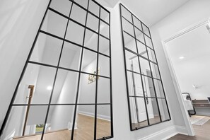 A room with a large mirror reflecting a door and a hallway.