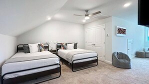A bedroom with two beds, a ceiling fan, a white door, and a bean bag chair. - Tee & Sea Paradise- Pool- Slps 11- Golf View-Grill (North Myrtle Beach)