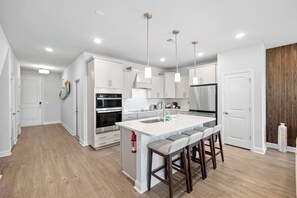 A modern kitchen with white cabinetry, a central island with bar stools, and a built-in oven.
