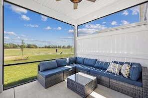 A covered outdoor seating area with a view of a golf course.