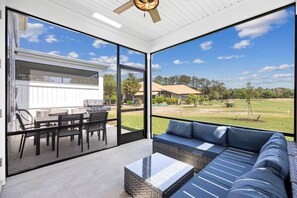 A modern outdoor living space with a patio, seating area, and a view of a residential neighborhood.