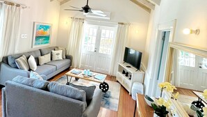 A spacious living room with a high ceiling, a ceiling fan, a sofa set, a television, and a dining area with a table and chairs. - Beachcombers villa, Porters Court, Fairmont beach passes, few meters to Lonestar (Porters)