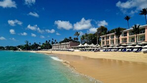 A beach resort with a row of sun loungers and umbrellas, a clear blue sky, and a calm sea. - Beachcombers villa, Porters Court, Fairmont beach passes, few meters to Lonestar (Porters)
