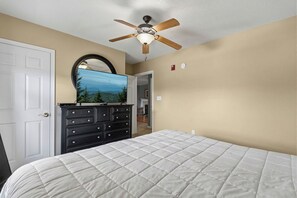 Un dormitorio con cama, cómoda, ventilador de techo y espejo.