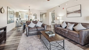 A spacious living room with a brown leather sofa, a wooden coffee table, and a dining area in the background. - 3 BR | City View | Updated | Free Dollywood Ticket | Indoor Pool (Pigeon Forge)