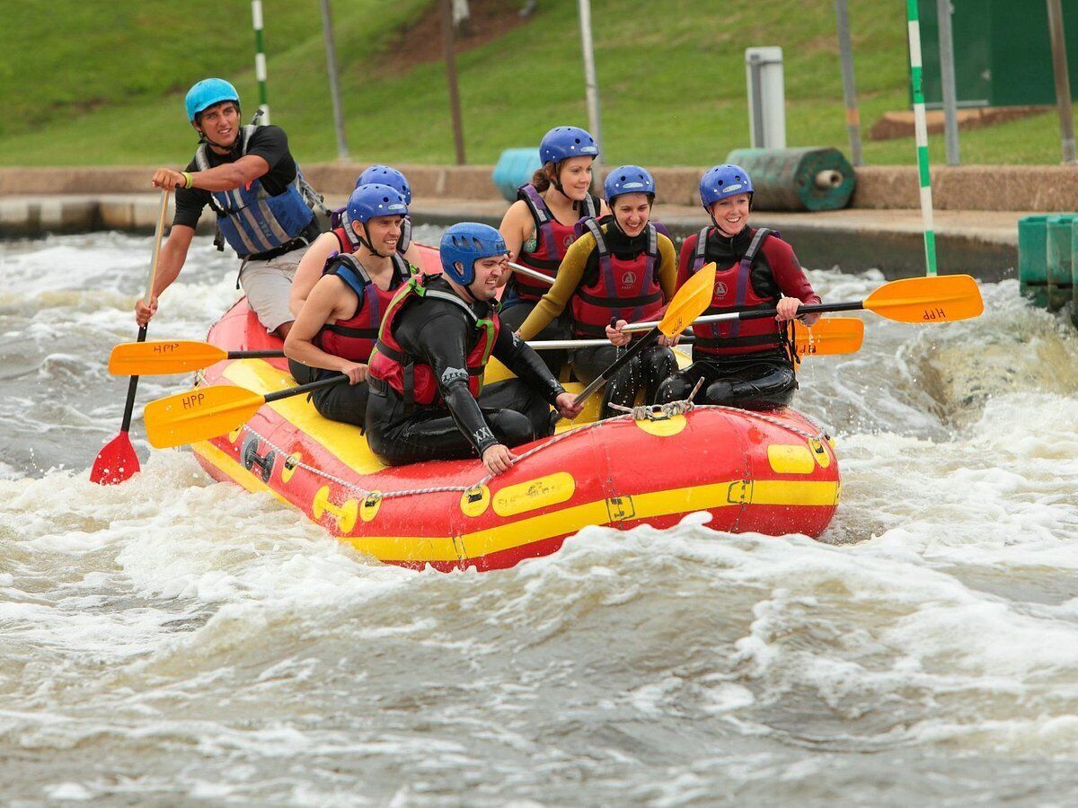 Un grupo de personas en un bote inflable rojo y amarillo navegando en aguas agitadas.