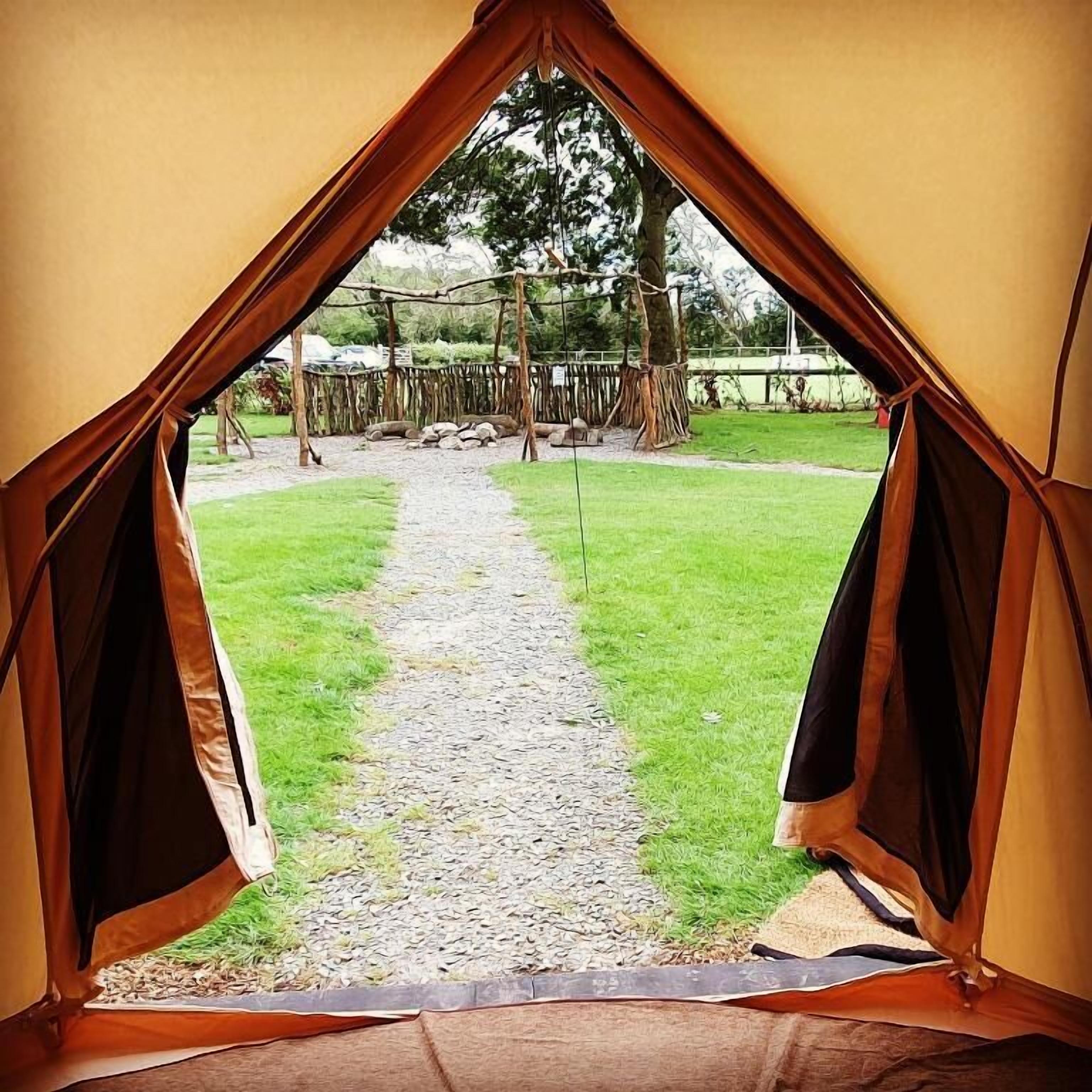 Uma tenda com um caminho de cascalho que leva a uma área cercada com árvores.