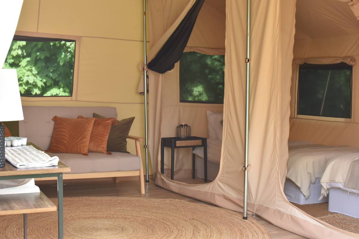 Ein Zelt mit Bett, einem kleinen Tisch und einer Couch.