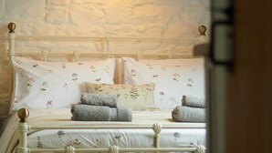 Een slaapkamer met een schuine plafond, een bed met bloemenbeddengoed en een hanglamp.