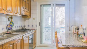 A kitchen with wooden cabinets, a gas stove, a sink, and a window with a view of the outdoors. - Apartament in Amalfi ID 4178 (Amalfi)