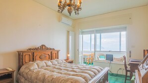 A bedroom with a large bed, a wooden dresser, a desk with a chair, and a window with a view. - Apartament in Amalfi ID 4178 (Amalfi)