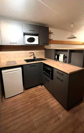 Uma cozinha compacta equipada com micro-ondas, forno, pia e lava-louças.
