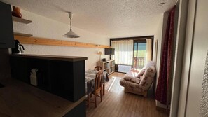 A compact living space with a kitchenette, a dining area, and a seating area with a view of the outdoors.