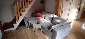 A living room with a grey sofa, two small tables, and a staircase.