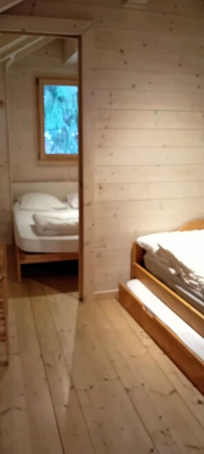 A wooden-paneled room with a bed, a window, and a door.