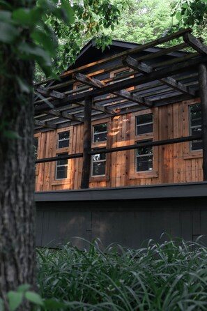 A wooden cabin with a wooden deck and multiple windows. - Quaint cottage in the woods with swim spa (Frazeysburg)