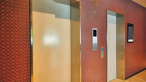 A hallway with three elevator doors, one of which has a patterned wall. - Y S Inn Naha Oroku Ekimae (Naha)
