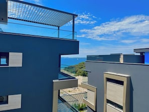 A modern building with a rooftop terrace overlooking a body of water. - Zados Luxury Residence (Zadar)
