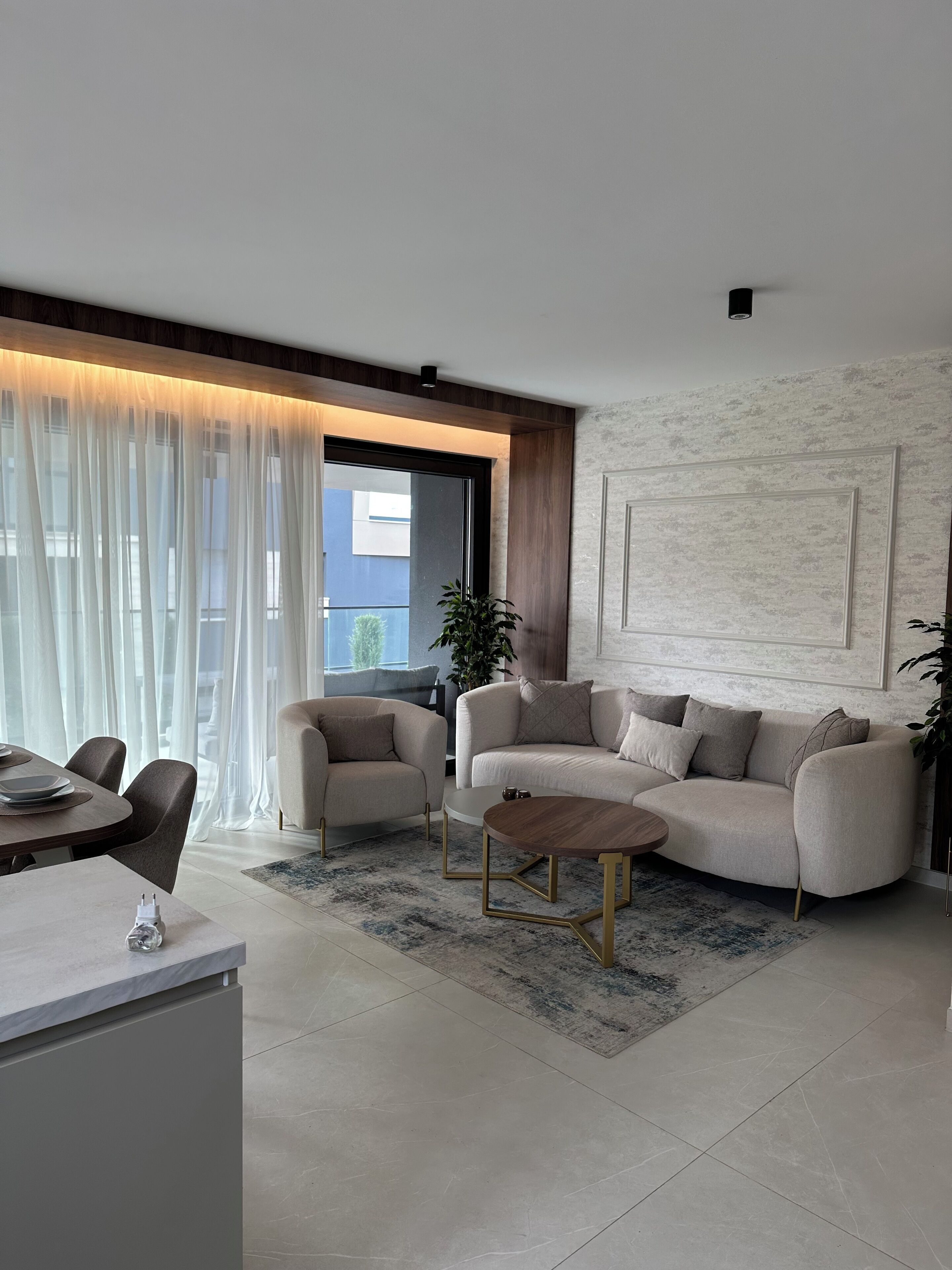 Una sala de estar moderna con un sofá, sillas, una mesa de centro y un comedor con mesa y sillas.