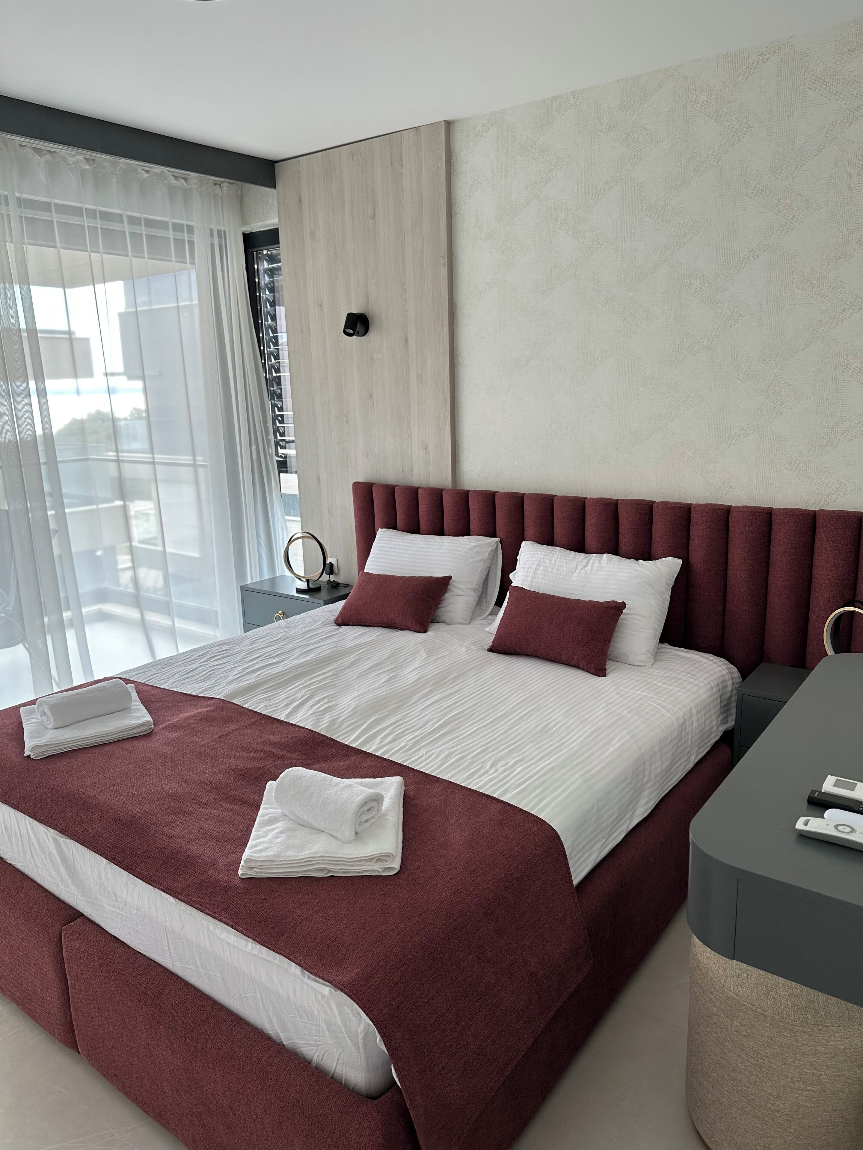 Een moderne hotelkamer met een groot bed, een bureau en uitzicht op de stad.