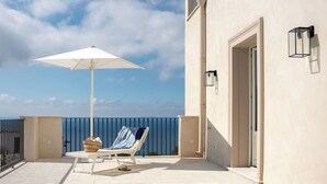 A balcony with a white umbrella, a lounge chair, and a wicker basket. - Tenuta Sirignano Villa Nord e Sud (Massa Lubrense)