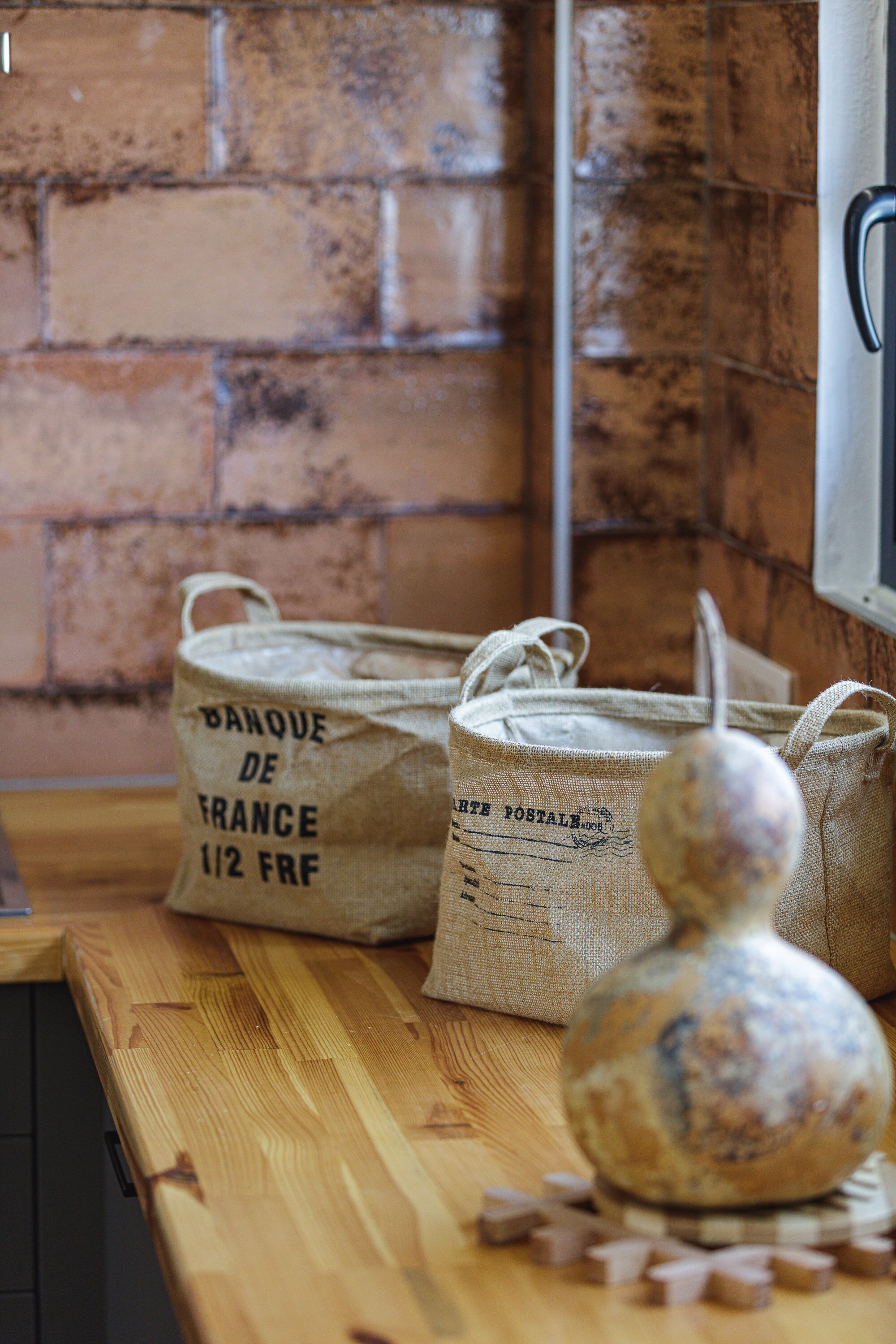 A wooden counter with burlap bags labeled "BANQUE DE FRANCE 1/2 FRF" and a decorative vase.