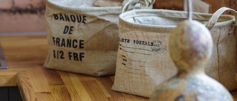 A wooden counter with burlap bags labeled "BANQUE DE FRANCE 1/2 FRF" and a decorative vase.