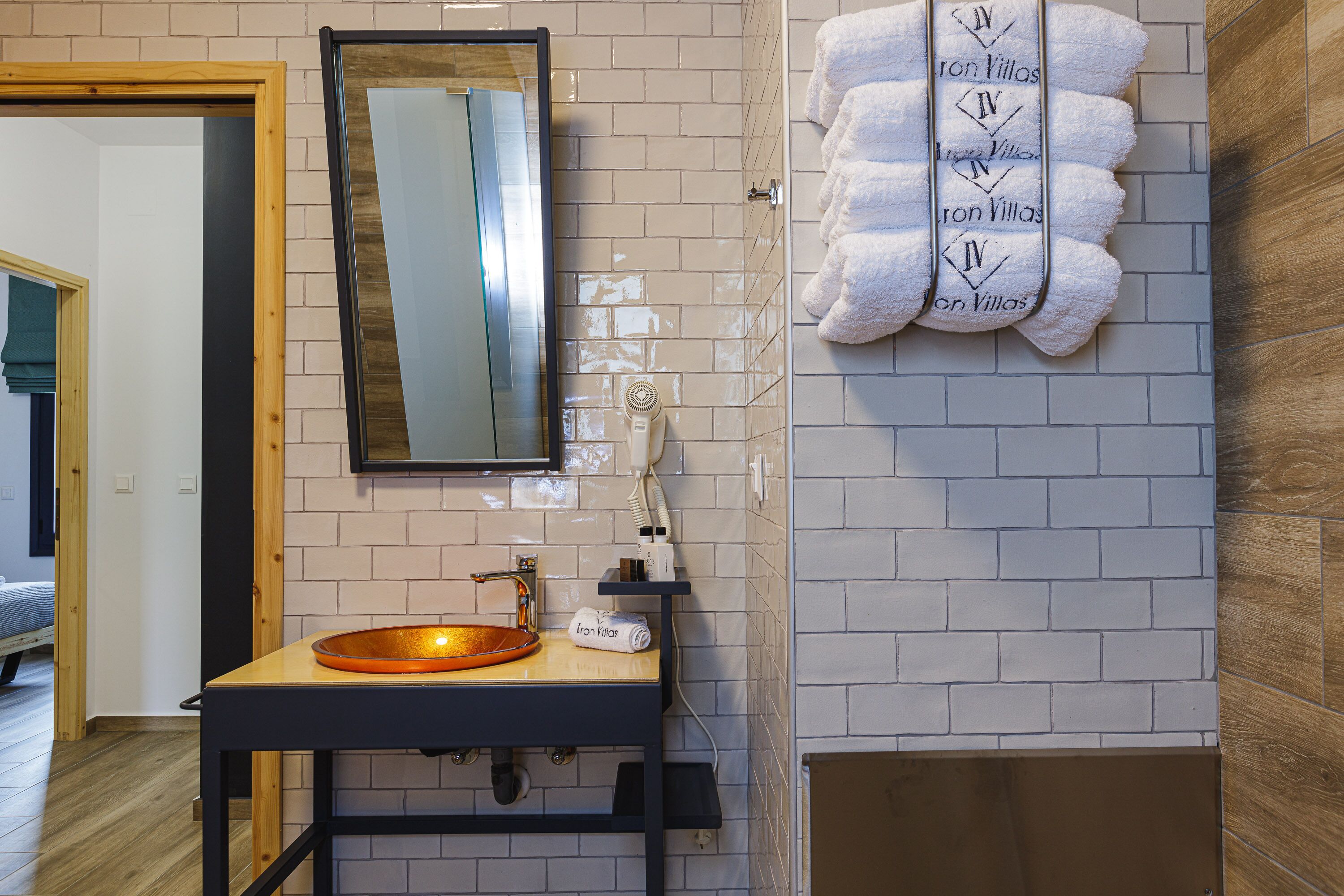 A bathroom with a wooden vanity, a round sink, a mirror, and a towel rack with towels.
